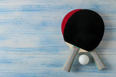 Two table tennis rackets. Table tennis rackets and a ball on a blue wooden table. sport game. top...