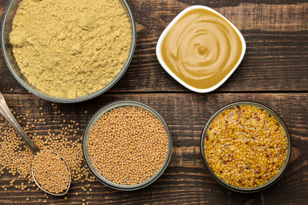 Mustard Different types of mustard, dry mustard grains sauce and mustard powder in a bowl on a brown...