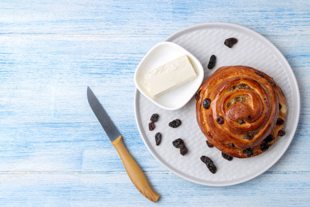 Delicious buns with raisins and butter on a light blue wooden table. fresh bakery. breakfast. bread....