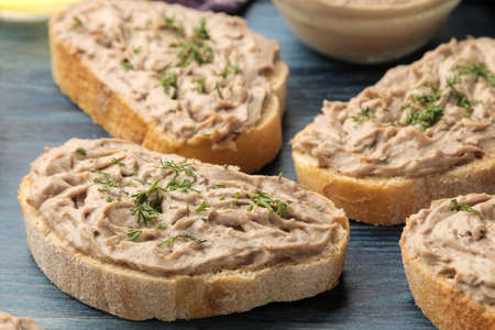 Fresh homemade chicken liver pate with herbs on bread on a blue wooden table. A sandwich. close-upの写真素材