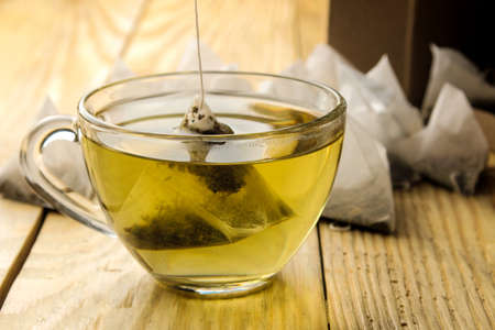 cup with tea and tea bag pyramid. close-up. on a wooden table. to make teaの写真素材