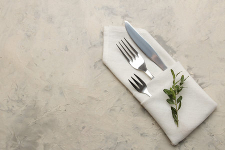 table setting. cutlery. Fork, knife in a white napkin on a light concrete table. top view