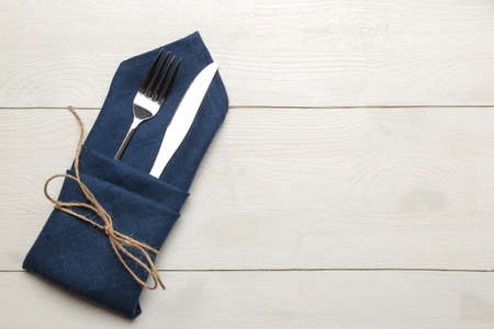 table setting. cutlery. Fork, knife in a blue napkin on a white wooden table. top viewの写真素材