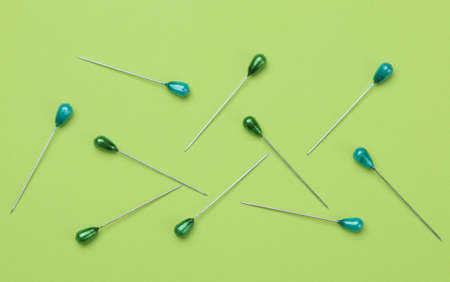 The concept of minimalism. Pins for sewing and needlework with green heads on a bright green background. top viewの写真素材