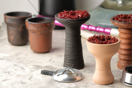 Tools and accessories for making hookah, clay bowls with tobacco, coconut charcoal on a light...