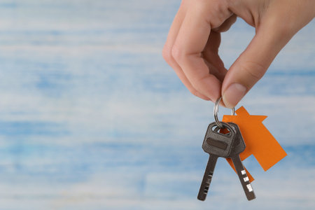 Home purchase concept. Keys with a keychain house in hand on a blue background