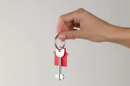 Home purchase concept. Keys with a keychain house in hand on a light background