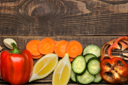 Set of sliced vegetables for making salads or other dishes on a brown wooden table. top view. place...