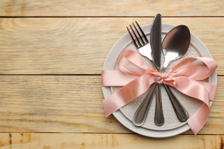 Table setting. Plate, glass and cutlery fork, spoon and knife on a natural wooden table. top viewの写真素材