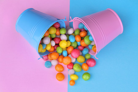 Multicolored round candy in a pink and blue decorative bucket on a pink and blue bright background....