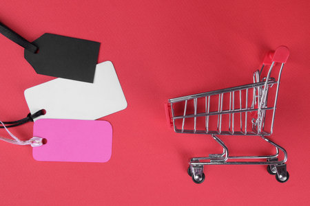 Black Friday. Shopping Price tags sale and shopping trolley on a red background. view from above