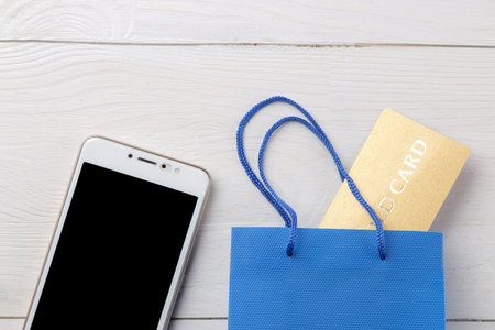 The concept of online shopping. Composition with discount cards and telephone on a light background.