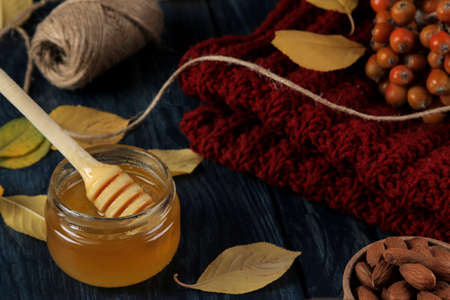 Autumn composition with honey, nuts and autumn yellow leaves on a blue wooden tableの写真素材