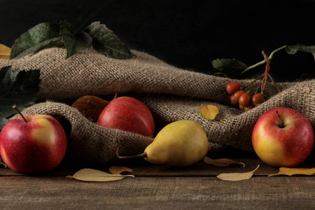 Autumn arrangement with fruit apples and pears and yellow autumn leaves on a brown wooden tableの写真素材
