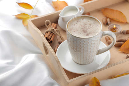 Autumn composition with hot coffee and yellow leaves on a tray on the bed.の写真素材