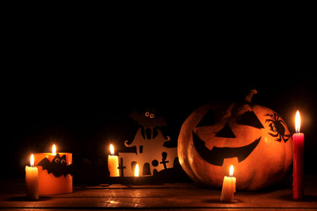 The concept of the holiday of Halloween. Halloween pumpkin head with candles inside and around on a wooden table on a black backgroundの写真素材