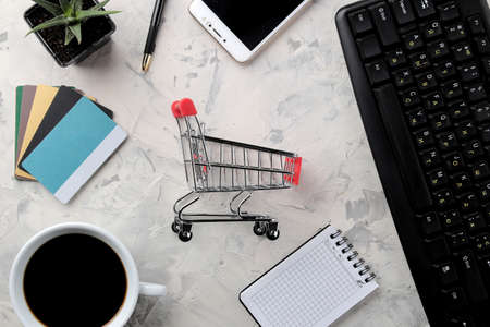 The concept of online shopping. Composition with discount cards and shopping trolley and telephone on a light background.の写真素材