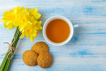 Bouquet of daffodils, spring flowers on a blue background. Tea and cookies. top view.の写真素材
