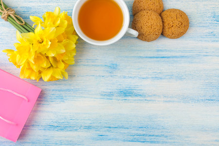 Bouquet of daffodils, spring flowers on a blue background. Tea and cookies. top view.の写真素材
