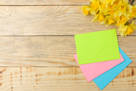 Spring flowers, yellow daffodils and multi-colored envelopes envelopes on a natural wooden background. place for textの写真素材