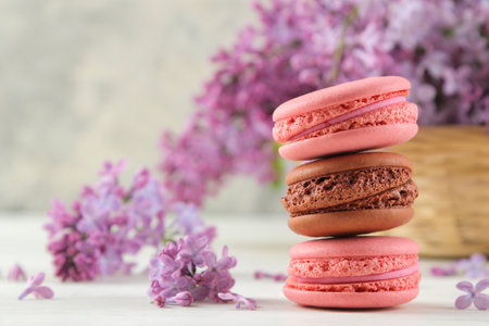 spring flowers. Twigs of blooming lilac in a wicker basket and macaroon cake on a light concrete backgroundの写真素材