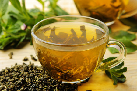 green tea. Hot tea in a cup with mint and dry tea leaves on a wooden background.の写真素材