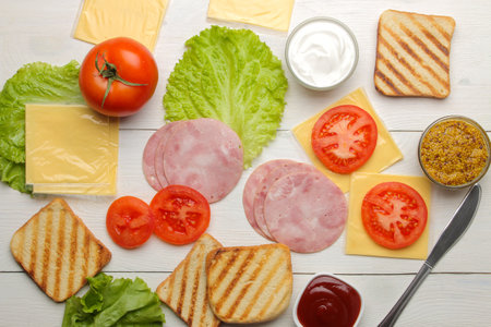 Sandwich. Ingredients for making sandwiches bread, ham, cheese, tomato and sauces on a white backgroundの写真素材