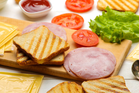 Sandwich. Ingredients for making sandwiches on a board of bread, ham, cheese, tomato on a white backgroundの写真素材