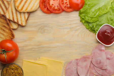 Sandwich. Ingredients for making sandwiches bread, ham, cheese, tomato and sauces on a wooden backgroundの写真素材