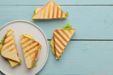 Sandwich on a plate with ham, cheese and tomato on a blue background. top viewの写真素材