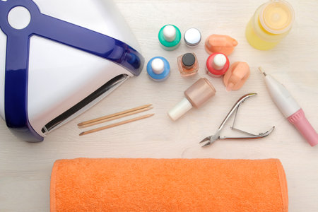 led lamp for nail extension and various gel polishes on a light background. view from above. tools for manicure and pedicure.の写真素材