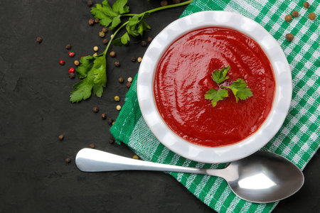 Delicious tomato soup on a black table, parsley and spices on a black table. top view.の写真素材