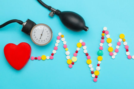 Cardiogram from various pills and a red heart on a blue background. top view. Cardiology and treatment of heart diseases.の写真素材
