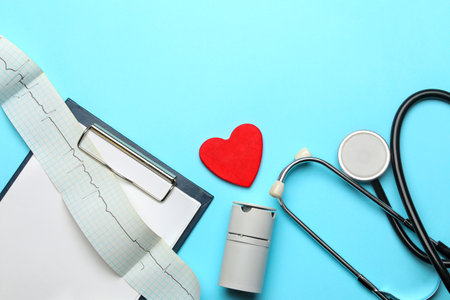 Stethoscope, red heart and cardiogram on a blue background. doctor's desk. top view and free space. Cardiology and treatment of heart diseases.の写真素材