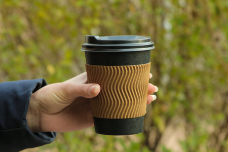 The girl holds a paper cup for hot drinks in her hands. coffee to goの写真素材