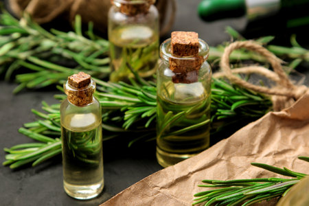 Natural rosemary essential oil in a glass bottle and a fresh sprig of rosemary on a black background. face and body skincare. spa.の写真素材