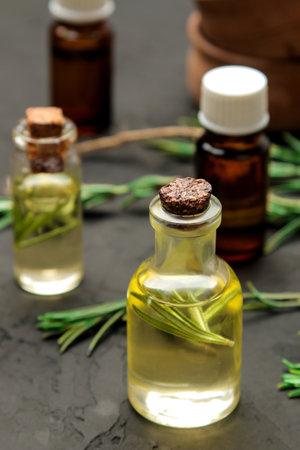 Natural rosemary essential oil in a glass bottle and a fresh sprig of rosemary on a black background. face and body skincare. spa.の写真素材