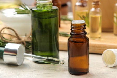 Natural rosemary essential oil in a glass bottle and a fresh sprig of rosemary on a light background. face and body skin care. spa.の写真素材