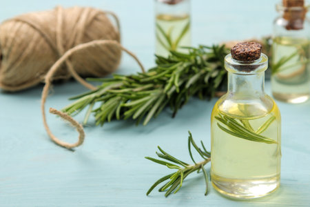 Natural rosemary essential oil in a glass bottle and a fresh sprig of rosemary on a blue table. face and body skincare. spa.の写真素材