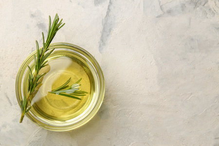 Natural rosemary essential oil in a glass bottle and a fresh sprig of rosemary on a light background. face and body skin care. spa.の写真素材