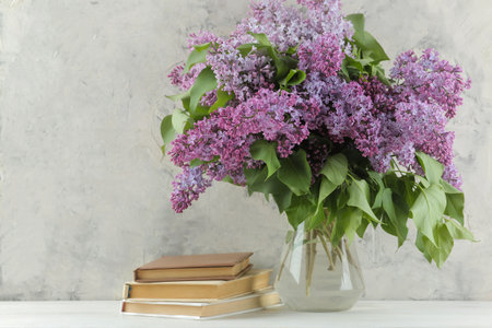 Spring bouquet of lilacs in a vase and books on a light backgroundの写真素材