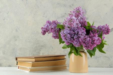 Spring bouquet of lilacs in a vase and books on a light backgroundの写真素材