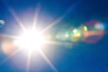 Sun and flare shining in the blue skyの写真素材