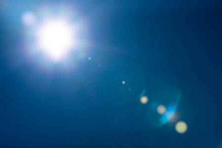 Sun shining in the blue sky, flare reflected there