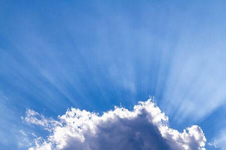 Sun rays through the white clouds background, blue sky with cloudsの写真素材