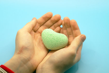 A heart-shaped bath bomb in close-up in the hands.の写真素材