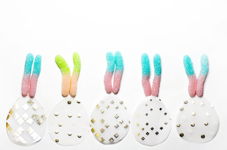 Multicolored marmalade in the shape of rabbit ears over paper eggs