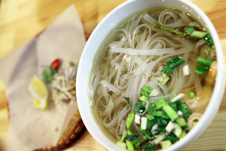 Vietnamese pho soup in a cafe, served with sprouted wheat and chili pepper