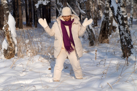 A happy woman stands in the forest with her hands raisedの写真素材