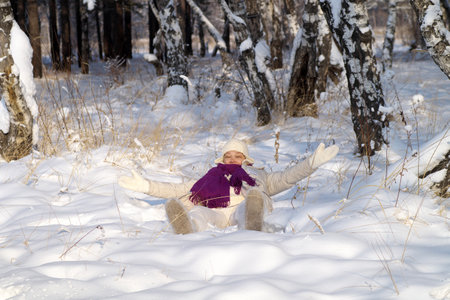 A happy woman walks through a snowy forestの写真素材